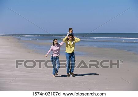 Stock Image - Parents playing with their daughter on the beach. Fotosearch