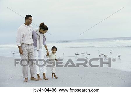 Parents walking with their daughter on the beach View Large Photo Image Stock Photograph - Parents walking with their daughter on the beach. Fotosearch