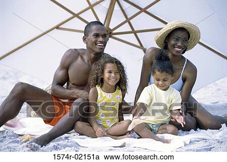Stock Image - Parents with their daughters on the beach. Fotosearch