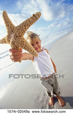 Portrait of a girl holding a starfish on the beach View Large Photo Image Stock Image - Portrait of a girl holding a starfish on the beach. Fotosearch