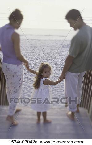 Portrait of a girl holding her parents hands on the beach View Large Photo Image Stock Image - Portrait of a girl holding her parents hands on the beach. Fotosearch