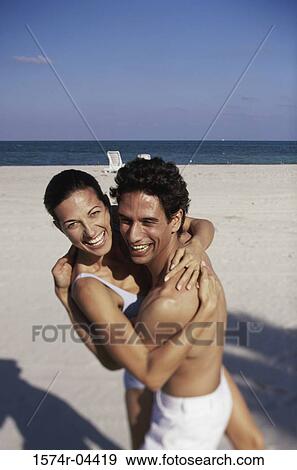 Portrait of a young couple embracing on the beach View Large Photo Image Stock Photo - Portrait of a young couple embracing on the beach. Fotosearch