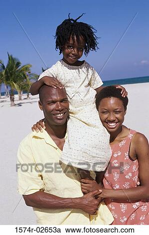 Stock Image - Portrait of parents carrying their daughter on their shoulders. Fotosearch