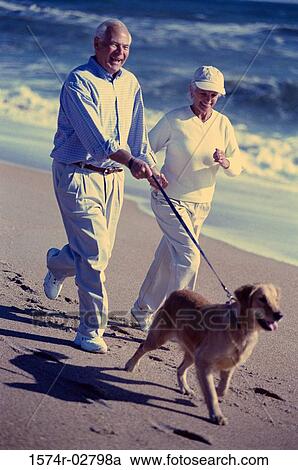 Senior couple jogging with their dog on the beach View Large Photo Image Stock Image - Senior couple jogging with their dog on the beach. Fotosearch