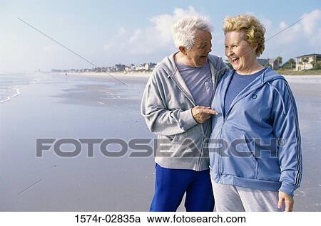 Stock Image - Senior couple standing on the beach. Fotosearch