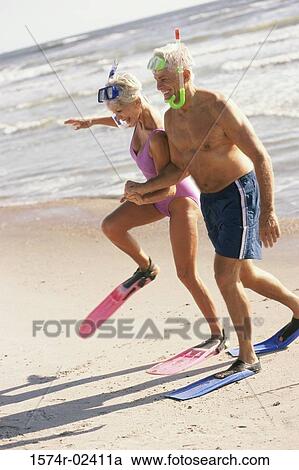 Senior couple walking on the beach wearing snorkeling gear View Large Photo Image Stock Image - Senior couple walking on the beach wearing snorkeling gear. Fotosearch