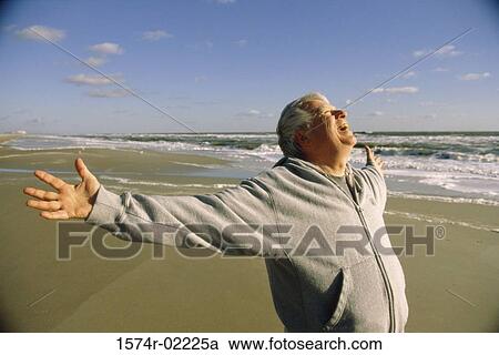 Stock Image - Senior man exercising on the beach. Fotosearch