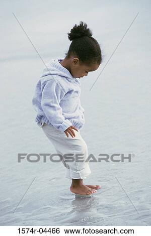 Side profile of a girl standing in water on the beach View Large Photo Image Stock Photograph - Side profile of a girl standing in water on the beach. Fotosearch