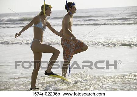 Side profile of a teenage couple walking on the beach wearing snorkels and flippers View Large Photo Image Stock Image - Side profile of a teenage couple walking on the beach wearing snorkels and flippers. Fotosearch