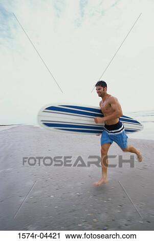 Side profile of a young man carrying a surfboard under his arm running on the beach View Large Photo Image Stock Image - Side profile of a young man carrying a surfboard under his arm running on the beach. Fotosearch