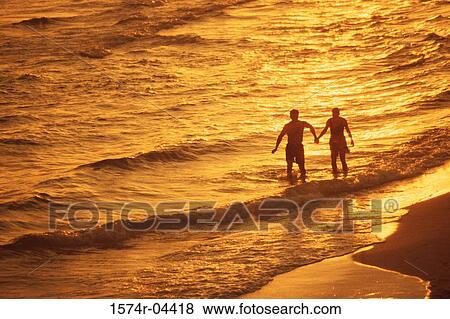 Stock Photo - Silhouette of a young couple on the beach. Fotosearch