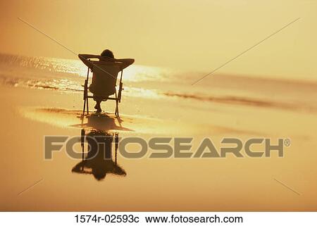 Silhouette of a young woman sitting in a chair on the beach View Large Photo Image Stock Image - Silhouette of a young woman sitting in a chair on the beach. Fotosearch