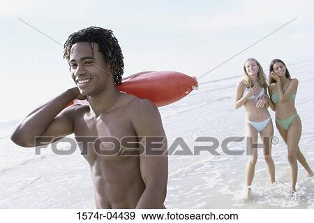 Teenage boy on the beach with two teenage girls behind him View Large Photo Image Stock Photo - Teenage boy on the beach with two teenage girls behind him. Fotosearch