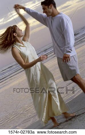 Stock Image - Young couple dancing on the beach. Fotosearch