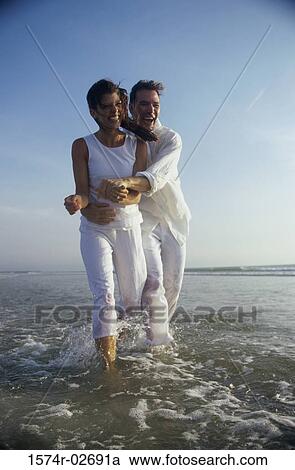 Stock Image - Young couple holding each other on the beach. Fotosearch
