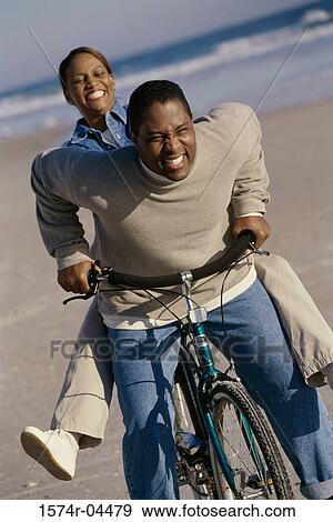 Young couple on a bicycle on the beach View Large Photo Image Stock Photo - Young couple on a bicycle on the beach. Fotosearch