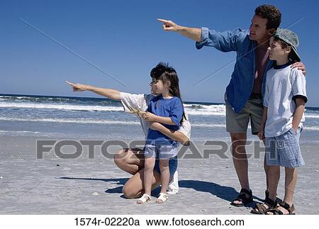 Young couple pointing on the beach with their son and daughter View Large Photo Image Stock Image - Young couple pointing on the beach with their son and daughter. Fotosearch
