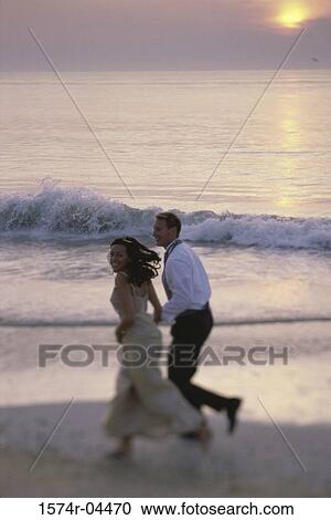 Young couple running on the beach View Large Photo Image Stock Image - Young couple running on the beach. Fotosearch