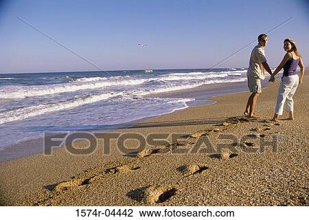 Stock Image - Young couple walking on the beach. Fotosearch