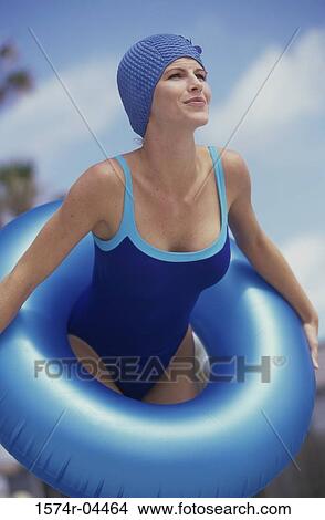 Young woman standing on the beach holding an inflatable ring View Large Photo Image Picture - Young woman standing on the beach holding an inflatable ring. Fotosearch