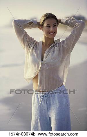 Stock Image - Young woman standing on the beach. Fotosearch