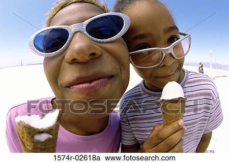 Stock Image - Close-up of a mother and her daughter holding ice cream cones. Fotosearch