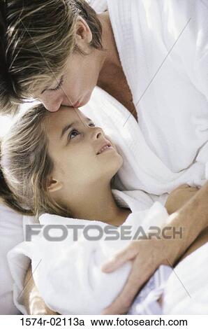 Stock Image - Close-up of a mother kissing her daughter on the forehead. Fotosearch