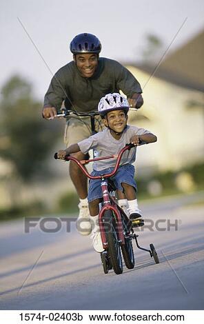 Stock Image - Father and his son riding a bicycle. Fotosearch
