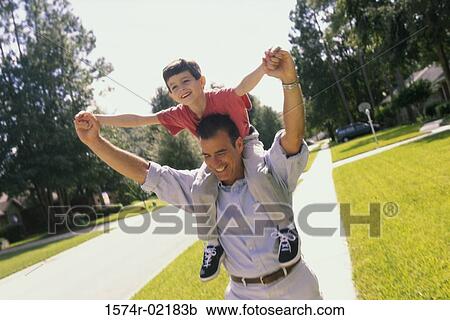 Stock Image - Father carrying his son on his shoulders. Fotosearch