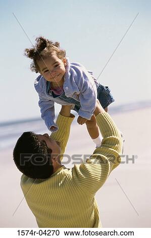 Father lifting his daughter on the beach View Large Photo Image Stock Image - Father lifting his daughter on the beach. Fotosearch