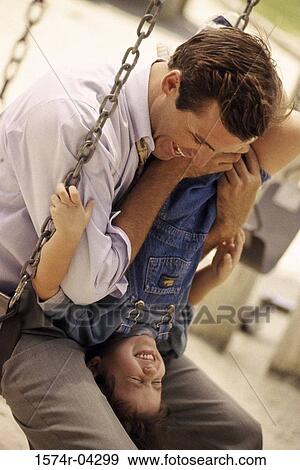 Stock Photo - Father sitting on a swing with his daughter. Fotosearch