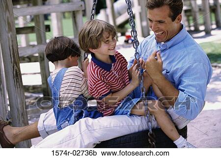 Stock Image - Father sitting on a swing with his two sons. Fotosearch