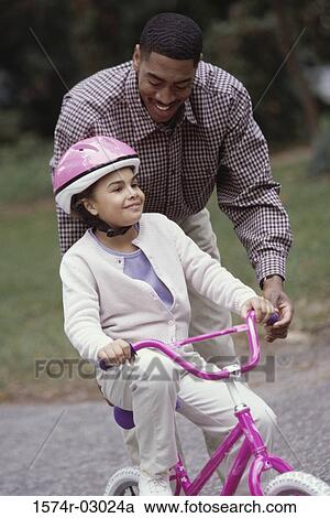 Father teaching his daughter cycling View Large Photo Image Stock Image - Father teaching his daughter cycling. Fotosearch