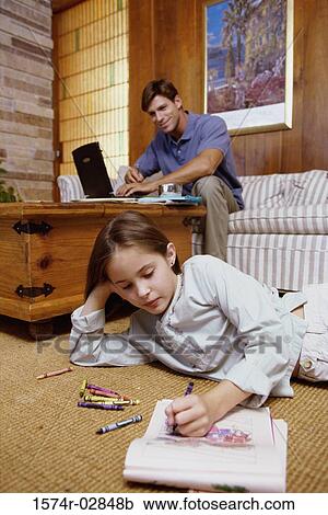 Girl lying on the floor with her father working on a laptop behind her View Large Photo Image Stock Image - Girl lying on the floor with her father working on a laptop behind her. Fotosearch