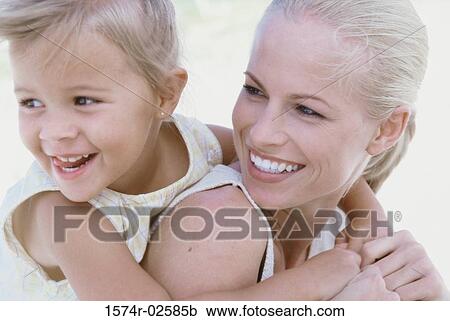 Stock Image - Girl riding piggyback on her mother. Fotosearch