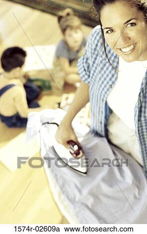 High angle view of a mother ironing clothes with her children playing nearby View Large Photo Image Stock Image - High angle view of a mother ironing clothes with her children playing nearby. Fotosearch