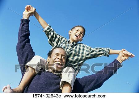 Low angle view of a father carrying his son on his shoulders View Large Photo Image Stock Image - Low angle view of a father carrying his son on his shoulders. Fotosearch