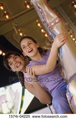 Stock Photography - Low angle view of a girl and her mother riding on a merry-go-round. Fotosearch