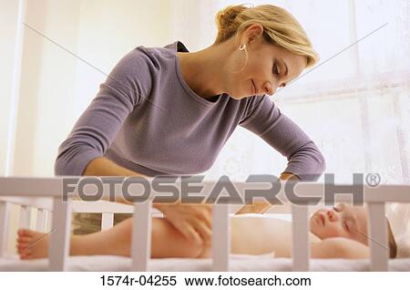 Mother adjusting sleeping her baby's diaper View Large Photo Image Stock Photography - Mother adjusting sleeping her baby's diaper. Fotosearch
