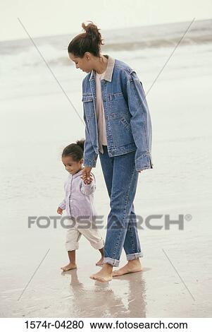 Mother and her daughter walking together on the beach View Large Photo Image Stock Image - Mother and her daughter walking together on the beach. Fotosearch