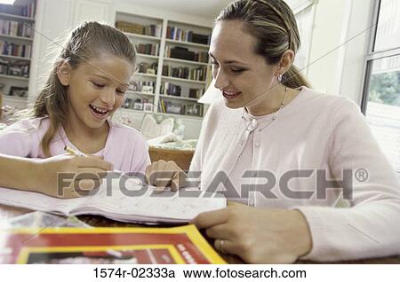 Stock Image - Mother assisting her daughter with her homework. Fotosearch