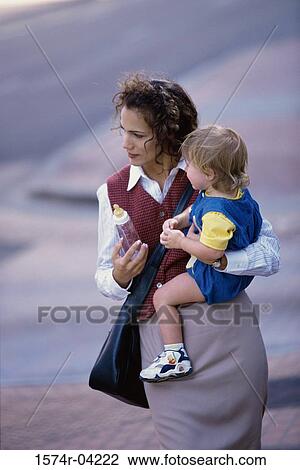 Stock Image - Mother carrying her daughter. Fotosearch