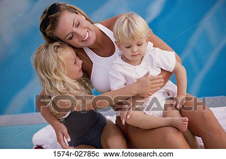 Mother holding her son and daughter beside a swimming pool View Large Photo Image Stock Image - Mother holding her son and daughter beside a swimming pool. Fotosearch