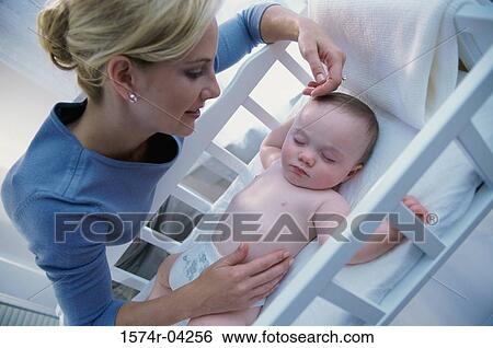 Stock Photograph - Mother looking at her baby boy in a crib. Fotosearch