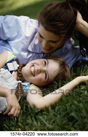 Mother lying on a lawn with her daughter View Large Photo Image Stock Image - Mother lying on a lawn with her daughter. Fotosearch