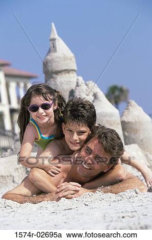 Portrait of a father lying on the beach with his son and daughter View Large Photo Image Stock Image - Portrait of a father lying on the beach with his son and daughter. Fotosearch