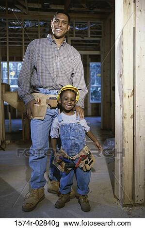 Stock Image - Portrait of a father standing with his son at a construction site. Fotosearch