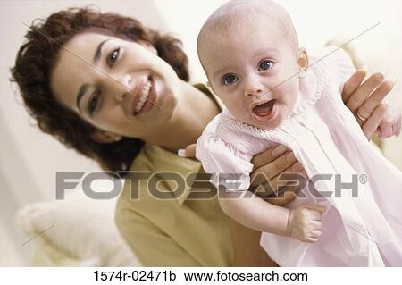 Stock Image - Portrait of a mother holding her baby girl. Fotosearch