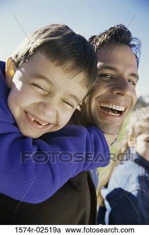 Stock Image - Portrait of a son riding piggyback on his father. Fotosearch