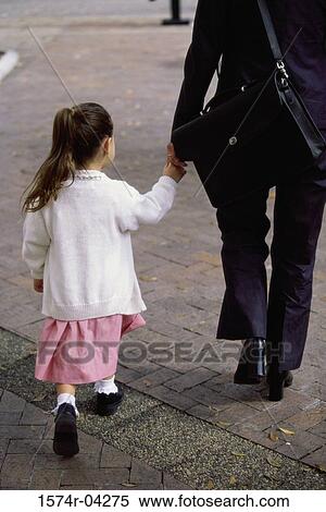 Rear view of a mother holding hands while walking with her daughter View Large Photo Image Stock Photography - Rear view of a mother holding hands while walking with her daughter. Fotosearch
